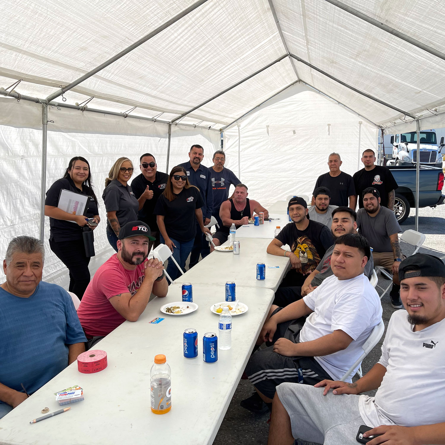 Team gathered around long white table inside event tent